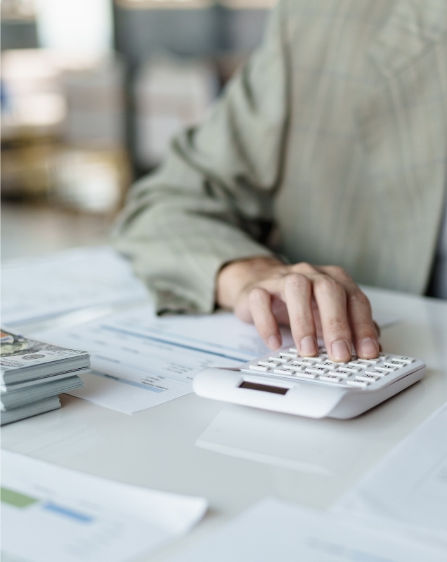 Scattered tax papers with glasses, pen, and rolled bills on top of a 1040 form